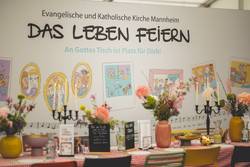 Quelle: Alexander Kästel, 2025-04-26 Evang und Kath Kirche auf dem Maimarkt 2025 by Alexander Kästel HD-25043954 Der gedeckte Tisch am Kirchenstand auf dem Maimarkt
