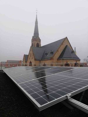 Bild einer Photovoltaik-Anlage mit Kirche im Hintergrund